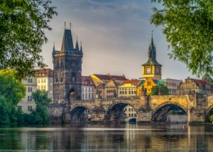 A bridge over a body of water named Karl Bridge with a castle in the background.