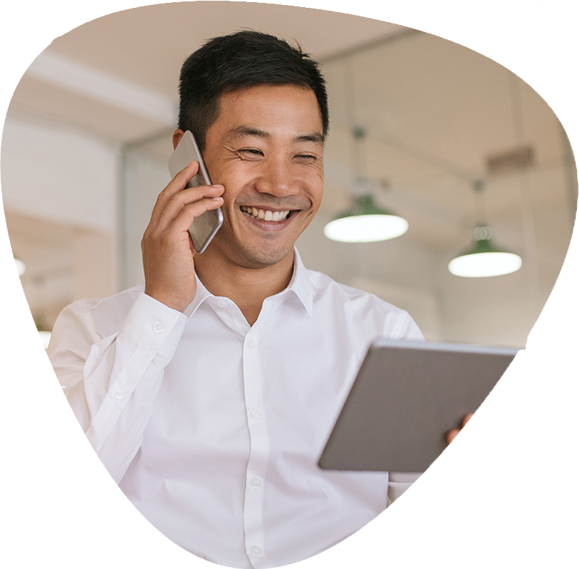 A man smiling while talking on a cell phone.